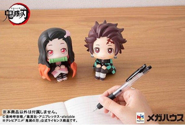 Lookup series Anime Figure Demon Slayer Tanjiro Kamado sitting with Nezuko Kamado figure in front of someone writing on notebook